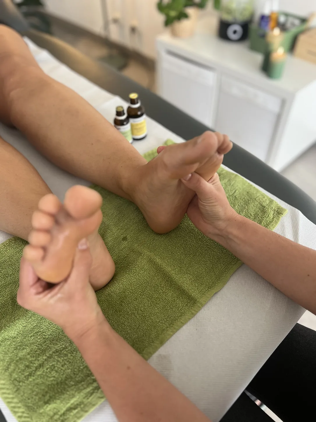 Mains d'Oksana sur les pieds pendant une séance de réflexologie plantaire à Bayonne